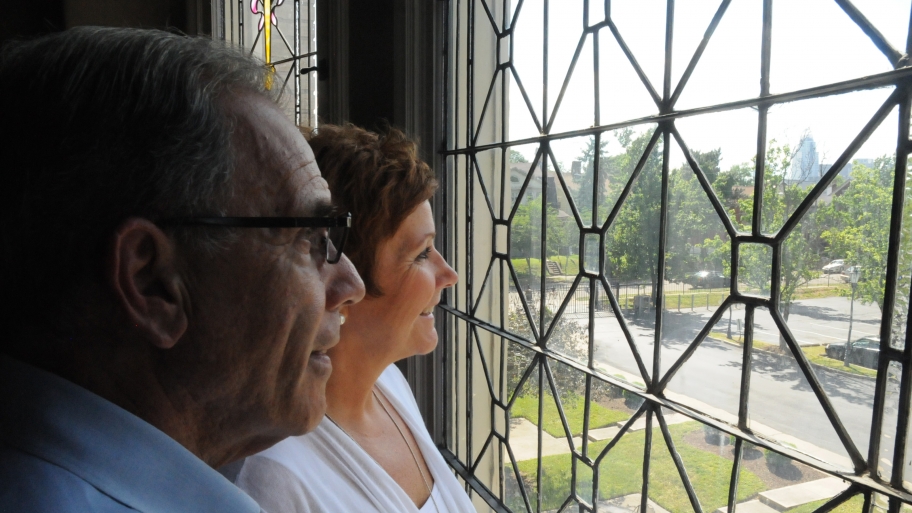 couple stares out apartment window at street